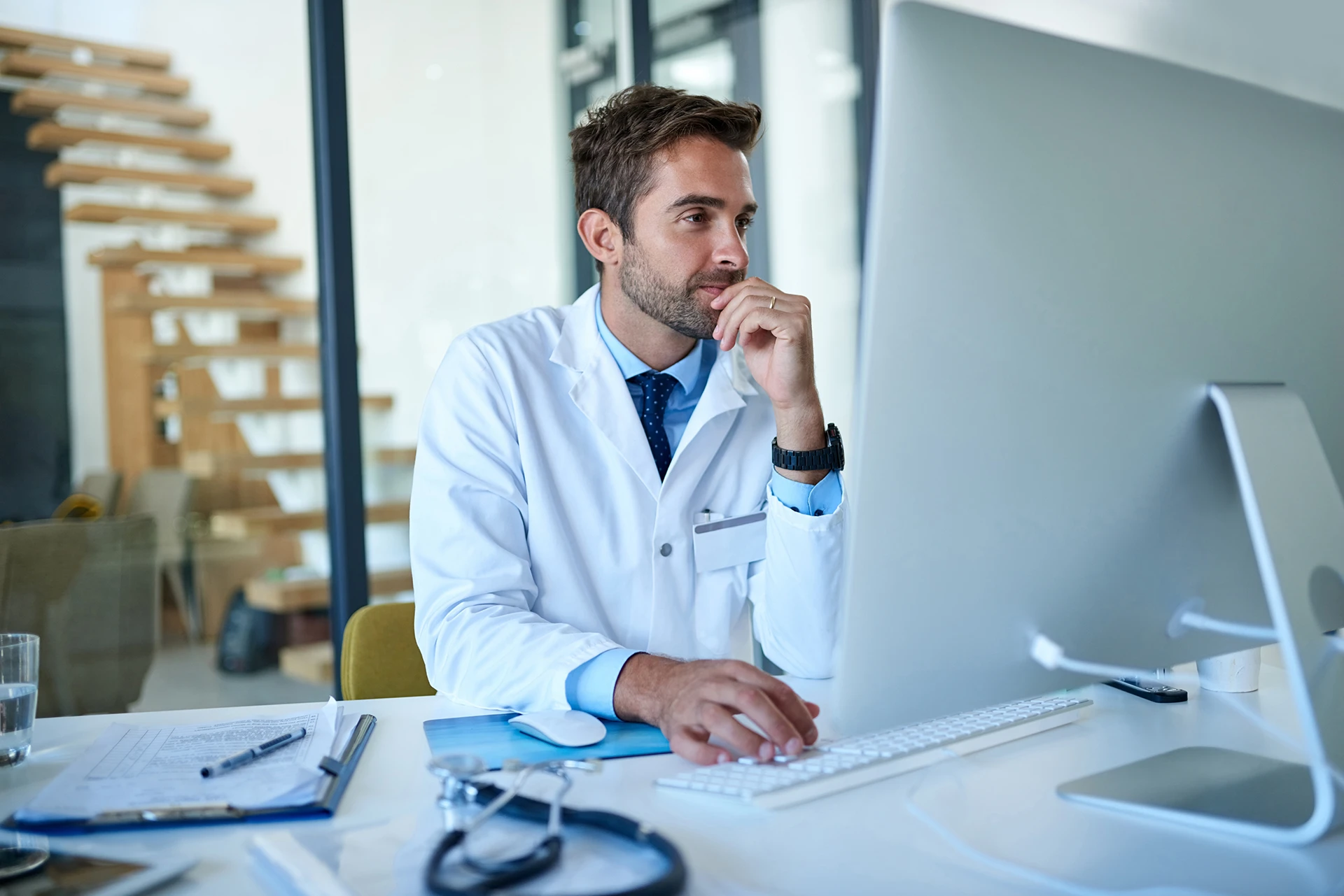 Médico con bata blanca utilizando una computadora